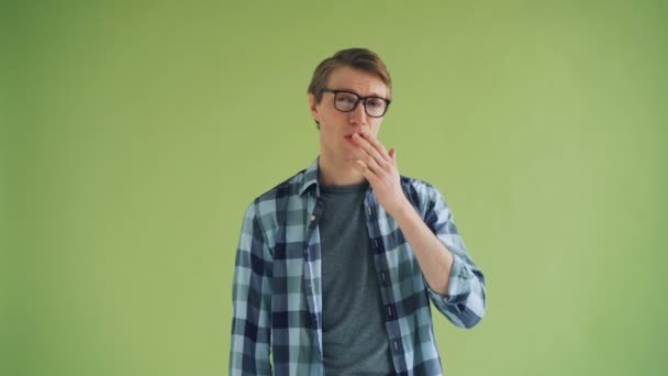 Retrato de un joven sonriente que envía un beso de aire y guiña un ojo sobre un fondo verde — Vídeos de Stock