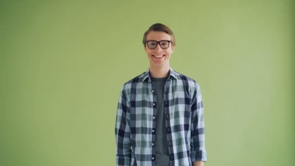 Портрет жизнерадостного хипстера улыбающегося и смеющегося на зеленом фоне — стоковое видео
