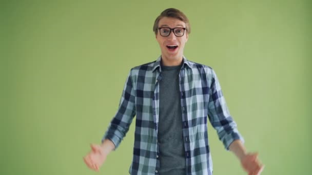 Opgewonden kerel kijkt naar camera lachen en het verhogen van armen op groene achtergrond — Stockvideo