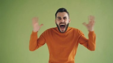 Yeşil arka planda silah kaldırma çığlık stresli genç adamın portresi