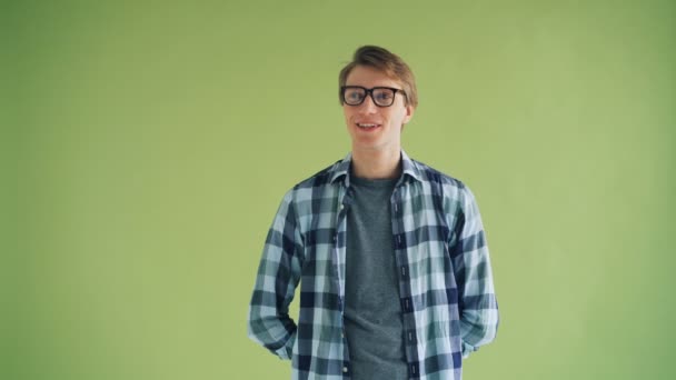 Portrait of handsome young man looking at camera and winking on green background — Stock Video