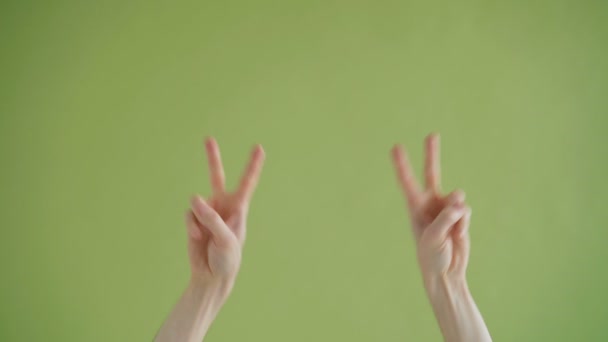 Close-up shot of human hands making v-sign moving dancing on green background — Stock Video