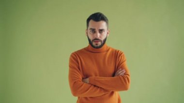 Kollar çapraz duran kameraya bakan mutsuz erkek öğrenciportresi