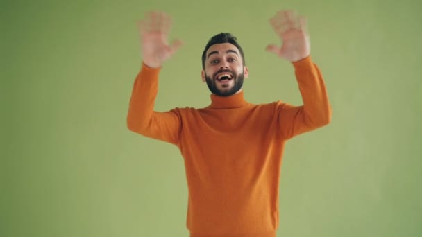 Porträtt av glad ung man vinka händer säger Hej tittar på kamera — Stockvideo