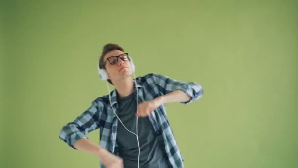 Retrato de un chico moderno escuchando música en auriculares y bailando divirtiéndose — Vídeo de stock