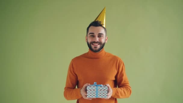 Portrait of joyful birthday man in party hat holding gift box and smiling — Stock Video