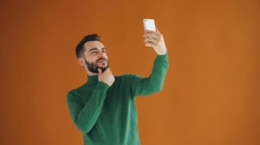 Yakışıklı sakallı adamın akıllı telefon kamerasıyla selfie çekmesinin portresi eğleniyor