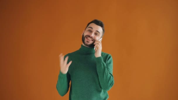 Cep telefonuyla konuşan ve gülümseyen neşeli genç adamın portresi — Stok video