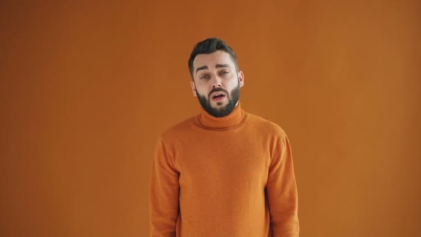 Portré unatkozó csípő körülnézett tátongó állva narancssárga háttér — Stock videók
