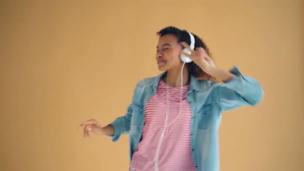 Portret van de schattige Afro-Amerikaanse dame luisteren naar muziek in koptelefoon dansen — Stockvideo