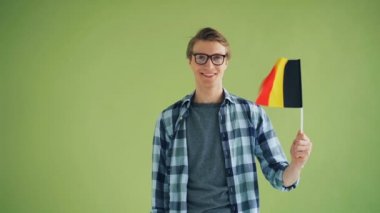 Almanya bayrağını sallayan ve gülümseyen genç adamın yavaş çekim portresi