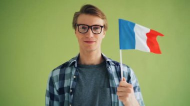 Fransa bayrağı tutan ve tek başına gülümseyen hipster yavaş hareket portresi