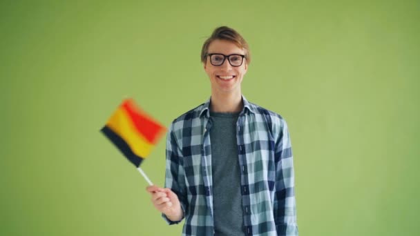 Slow motion of happy guy waving German flag standing on green background — Stock Video