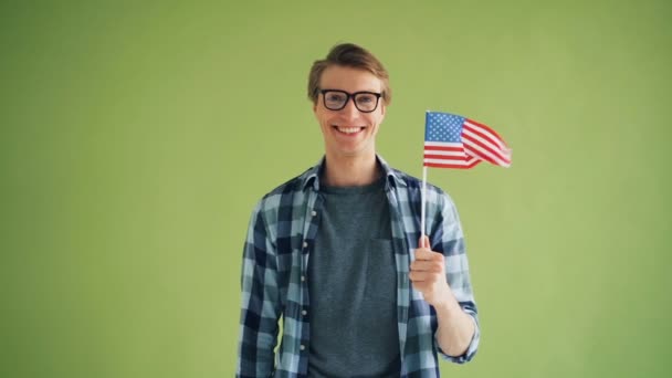 Portret amerykańskiego patrioty trzymając flagę USA uśmiechniętą patrząc na kamerę — Wideo stockowe
