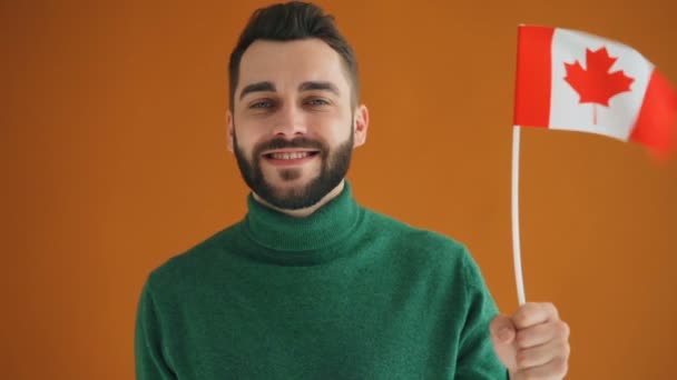 Slow motion portrait of bearded young student with Canadian flag smiling — Stock Video