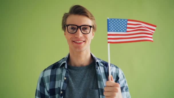 Slow motion portrait of young man with American national flag smiling — Stock Video