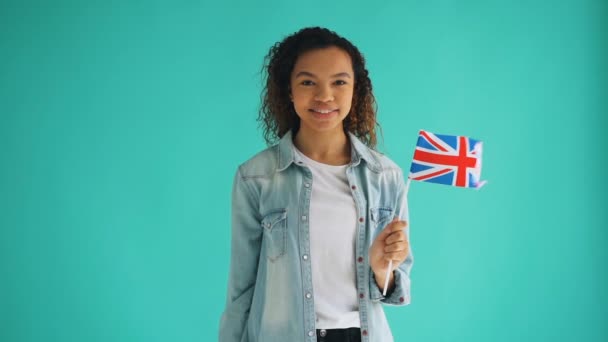 Cámara lenta de linda dama afroamericana con bandera nacional británica sonriendo — Vídeos de Stock