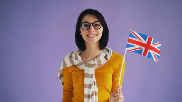 Cámara lenta de la atractiva dama británica sosteniendo la bandera de Gran Bretaña sonriendo — Vídeos de Stock