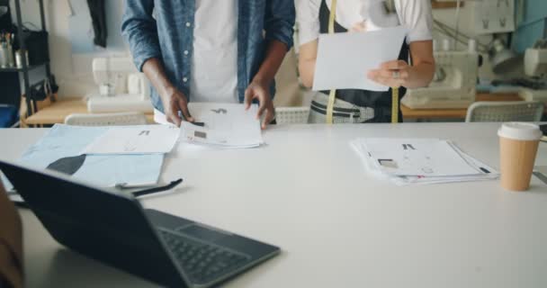 Tiro bajo de diseñadores de moda modernos que trabajan con bocetos en la mesa de coser — Vídeos de Stock