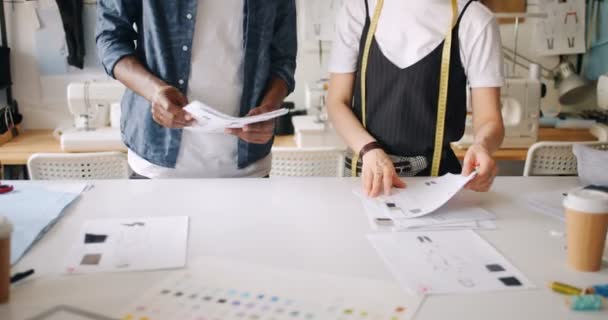 Diseñadores de ropa trabajando con bocetos poniendo papeles en la mesa señalando — Vídeos de Stock