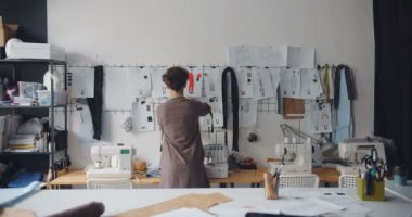 Terzi genç bayan duvara yeni giysi koleksiyonu planlama çizimleri dokunaklı