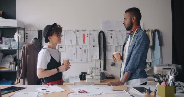 Chica y chico trabajadores de estudio de moda hablando sosteniendo café para ir a relajarse — Vídeo de stock