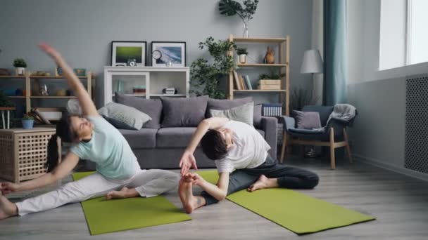 Férj és feleség stretching test és a lábak otthon pihentető pillangó helyzetben — Stock videók