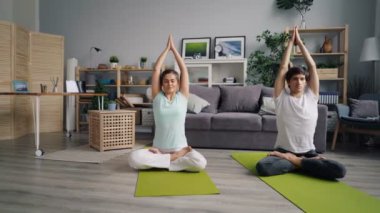 Genç bayan nilüfer pozisyonunda oturan yakışıklı kocası ile evde meditasyon