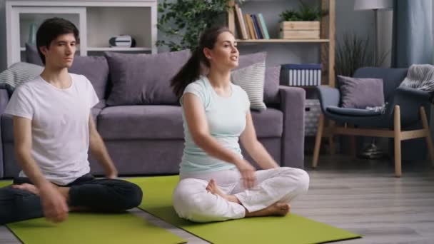 Flickvän och pojkvän utövar hemma sedan koppla av i Lotus position — Stockvideo