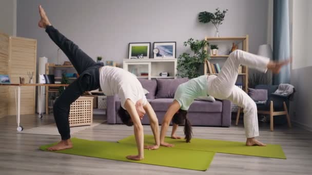 Esposo y esposa haciendo deportes en casa practicando la posición de cangrejo relajándose en el suelo — Vídeos de Stock