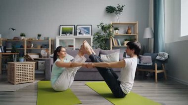 Evde egzersiz yapan mutlu gençler yerde oturan çiftler için yoga yapıyor