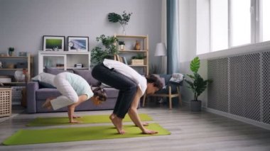 Mutlu çift birlikte evde egzersiz kollarında yoga dengeleme yapıyor