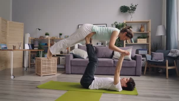 Man en vrouw doen yoga oefeningen in paar kerel ondersteuning balanceren meisje — Stockvideo