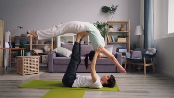 Jovencita haciendo yoga con novio practicando el equilibrio con apoyo — Vídeos de Stock