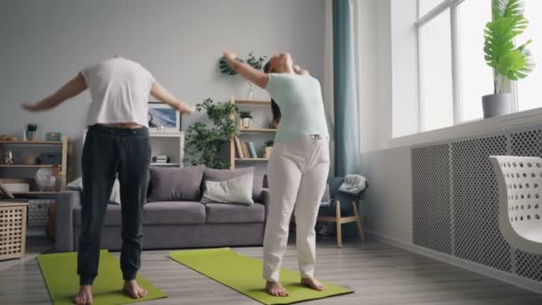 Man och hustru gör yoga tillsammans hemma njuter av avkopplande praktik — Stockvideo