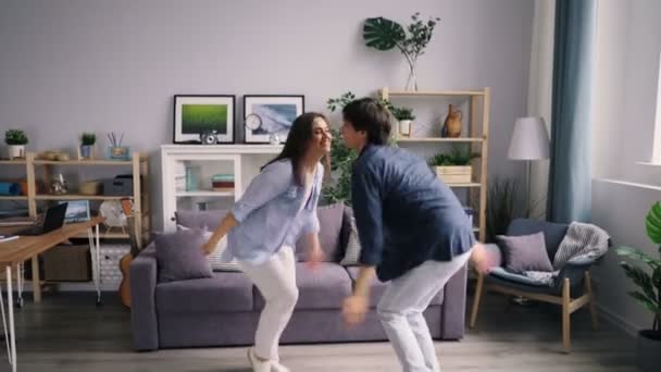 Menina e cara jovens felizes dançando em casa relaxando e rindo desfrutando da vida — Vídeo de Stock