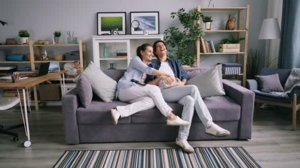 Powiększ radosną parę oglądając komedię w TV śmiech jedzenia popcorn w domu — Wideo stockowe