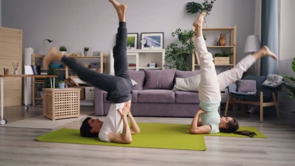 Casal desportivo exercitando em casa fazendo ioga juntos praticando asanas invertidas — Vídeo de Stock