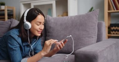 Neşeli genç bayan dokunma Smartphone ekran kulaklık müzik dinleme