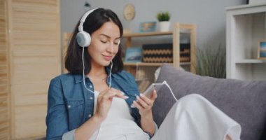 Akıllı telefon kullanarak kulaklıkta müzik dinleyen güzel kız yavaş hareket