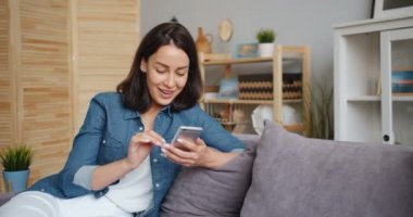 Güzel kadının akıllı telefona bakarak iyi haber alma gülümseyen yavaş hareket