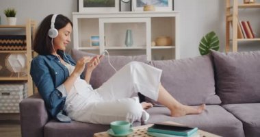 Akıllı telefon kullanarak neşeli kız ve modern kulaklıklar müzik dinleme