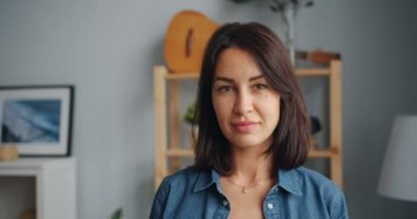 Evde gülümseyen kamera bakarak büyüleyici genç kadının yavaş hareket portre