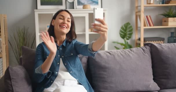 Câmera lenta de mulher atraente fazendo videochamada usando smartphone falando — Vídeo de Stock