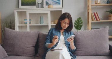 Evde oturan akıllı telefon ekranına bakarak dizüstü güzel kız yazma