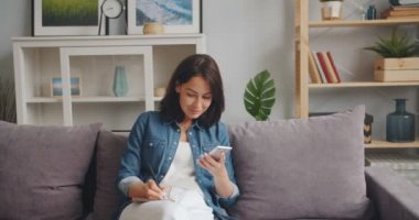 Ekran ve yazma Notebook bakıyor akıllı telefon tutan genç kadın