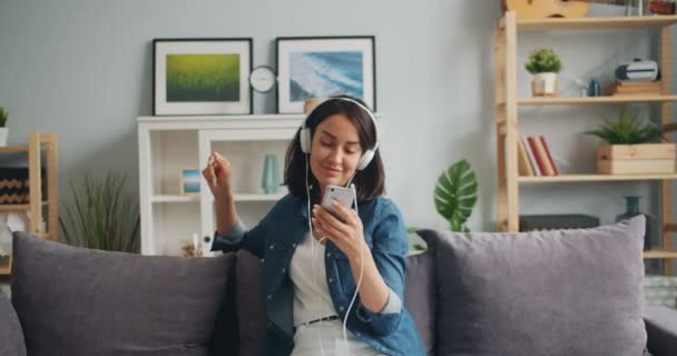 Rallentatore di giovane signora che ascolta musica utilizzando smartphone con cuffie — Video Stock