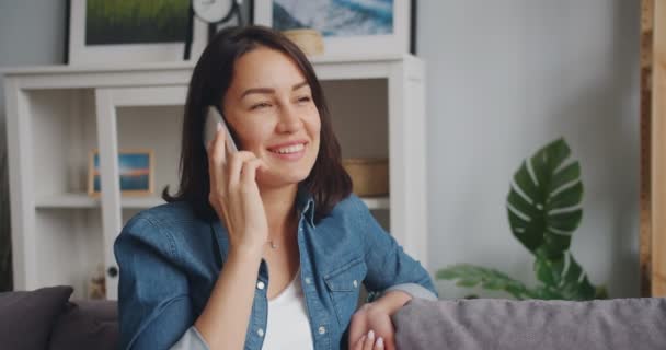 Mouvement lent de la jeune femme parlant sur son téléphone portable et souriant à la maison — Video