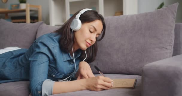 Movimento lento da jovem senhora desenho imagem e ouvir música em fones de ouvido — Vídeo de Stock