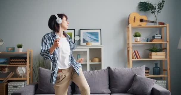 Menina elegante em fones de ouvido dançando ouvir música segurando smartphone — Vídeo de Stock
